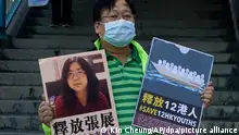 28.12.2020, China, Hongkong: Ein pro-demokratischer Aktivist zeigt zwei Plakate vor dem Verbindungsbüro der chinesischen Zentralregierung. Auf einem Plakat ist ein Foto der chinesischen Journalistin Zhang Zhan zu sehen. Zhang, eine ehemalige Anwältin und Journalistin aus Shanghai, wurde wegen ihrer Berichterstattung über den ersten Ausbruch des Coronavirus in Wuhan zu vier Jahren Gefängnis verurteilt. Die Aktivisten fordern die Freilassung von Zhang, sowie der 12 Hongkonger Aktivisten, die von den chinesischen Behörden auf See festgehalten werden. Foto: Kin Cheung/AP/dpa +++ dpa-Bildfunk +++