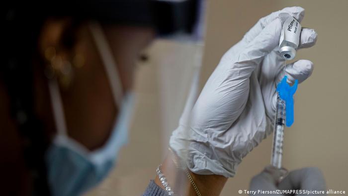 Медик набирает в шприц вакцину от коронавируса