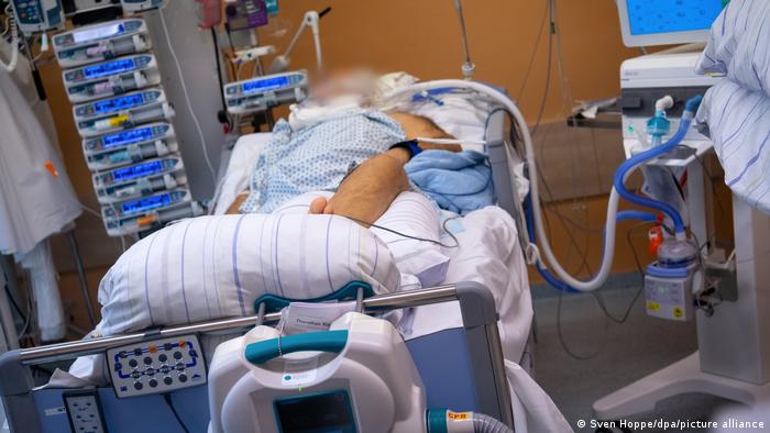 A COVID patient lies in a hospital bed in an artificial coma