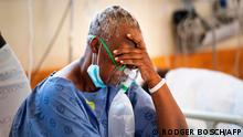 TOPSHOT - A patient with the COVID-19 breaths in oxygen in the COVID-19 ward at Khayelitsha Hospital, about 35km from the centre of Cape Town, on December 29, 2020. - The patents in this ward are not critically serious, but do require oxygen and to lie down. South Africa has become the first African nation to record one million coronavirus cases, according to new data published by the country's health ministry on December 27, 2020. Currently suffering a second wave of infections, of which the majority are a new variant of the coronavirus, South Africa is the hardest hit country on the African continent. (Photo by RODGER BOSCH / AFP)