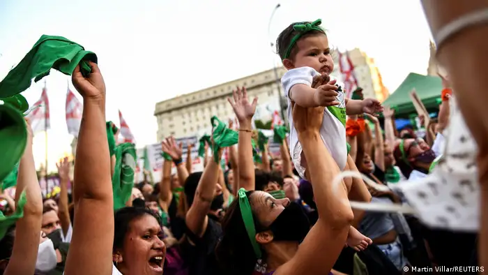 Celebraciones en el Congreso argentino por la nueva ley del aborto legal, seguro y grautito: una mamá levanta a su bebé, que lleva una vincha verde en la cabeza.