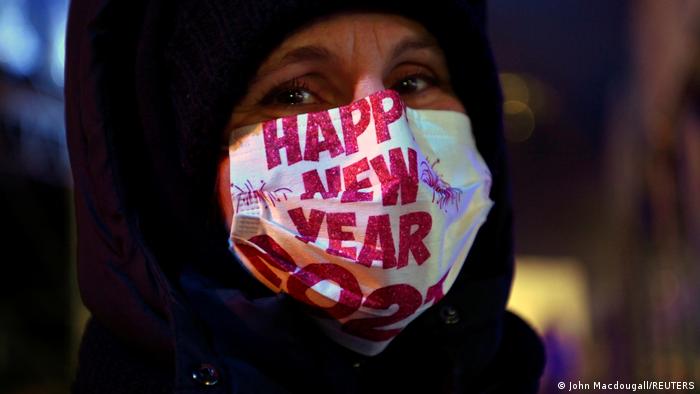 A security staff wears a face mask with lettering 'Happy New Year 2021'