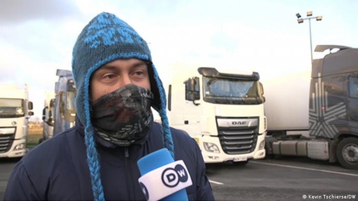 Yuri, a truck driver from Belarus, in a mask talking into a DW microphone