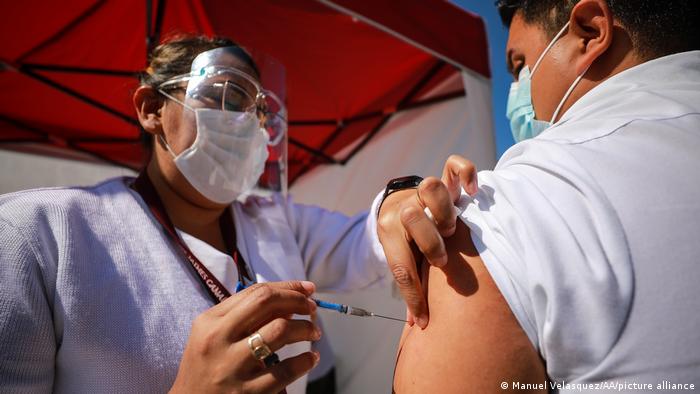 A nurse gives a Pfizer/BioNTech vaccine to a medical worker at a military camp in Mexico City.