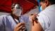 The image shows a Mexican man receiving a COVID-19 vaccination from a nurse