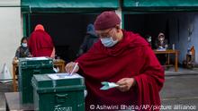 An exile Tibetan Buddhist monk wearing a mask as a precaution against the coronavirus casts his ballot in Dharmsala, India, Sunday, Jan. 3, 2021. Exile Tibetans Sunday voted in the first round to elect a new political leader and members of the Tibetan parliament in exile. (AP Photo/Ashwini Bhatia)