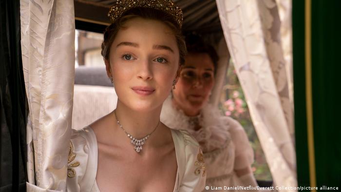 Phoebe Dynevor in Victorian era dress looks out of a horse-drawn coach.