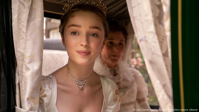 Phoebe Dynevor in Victorian era dress looks out of a horse-drawn coach.