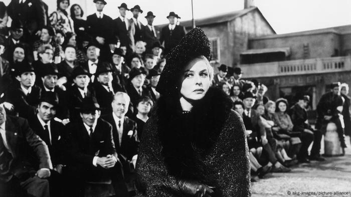 A woman dressed in black sits in front of a crowd