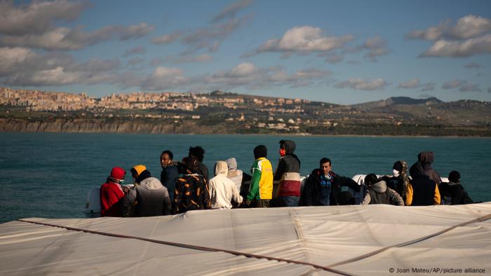 Migrants look at the coast of Italy on board an Open Arms vessel after being rescued in the Mediterranean Sea