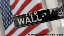 FILE - In this Aug. 16, 2007, file photo, the flags on the facade of the New York Stock Exchange provide a backdrop for a Wall Street street sign. Global stock markets were mostly lower Tuesday, Sept. 16, 2014, as jittery investors played it safe ahead of a potentially pivotal Federal Reserve meeting and the referendum on Scotland's independence on Thursday. (AP Photo/Richard Drew, File)