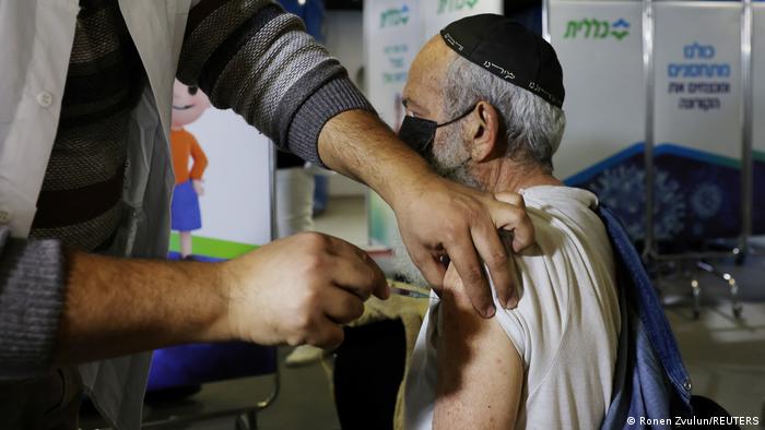 Homem aplica injeção em braço de outro homem sentado