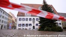 Ein Absperrband hängt auf dem Marktplatz vor einem Weihnachtsbaum und dem Rathaus. Landesweit hat laut Robert-Koch-Institut RKI nunmehr der Landkreis Meißen mit 492,7 den höchsten Inzidenzwert.