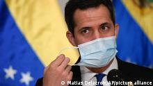 Venezuelan opposition leader Juan Guaido removes his protective face mask as he prepares to speak at a press conference in Caracas, Venezuela, Saturday, Dec. 5, 2020 a day before parliamentary elections. Polling places open Sunday to elect members of the National Assembly in a vote championed by President Nicolás Maduro but rejected as a fraud by the nation's most influential opposition politicians. (AP Photo/Matias Delacroix)