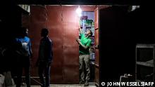 A man closes his shop ahead of curfew in Dakar on January 6, 2021. - Senegalese President Macky Sall announced on the evening on January 6 the state of emergency with a night curfew for two regions including Dakar to stop the rise of the coronavirus. (Photo by JOHN WESSELS / AFP)