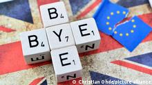 Würfelbuchstaben formen den Schriftzug Bye-bye auf der Fahne von Großbritannien neben einer zerrissenen EU-Fahne