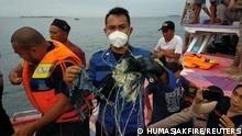 A member of the rescue team looking for an Indonesian plane that lost contact after taking off from the capital Jakarta holds suspected debris, at sea, January 9, 2021, in this picture obtained from social media. INSTAGRAM @HUMASJAKFIRE/via REUTERS THIS IMAGE HAS BEEN SUPPLIED BY A THIRD PARTY. MANDATORY CREDIT. NO RESALES. NO ARCHIVES.