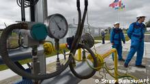 Employees stand next to a pipeline at the East Poltava gas booster compressor station not far from Ukrainian city of Poltava, after a ceremony marking the opening of the new station, on June 27, 2014. The opening of the new station is part of an ambitious plan to modernize the Ukrainian gas production infrastructure. AFP PHOTO / SERGEI SUPINSKY (Photo by SERGEI SUPINSKY / AFP)