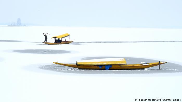 قایقران های هندی در پی بارش سنگین برف در سریناگار در هندوستان در جهیلی یخ زده ماهی می گیرند.