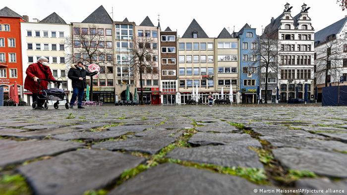 People cross an empty square in downtown in Cologne Germany