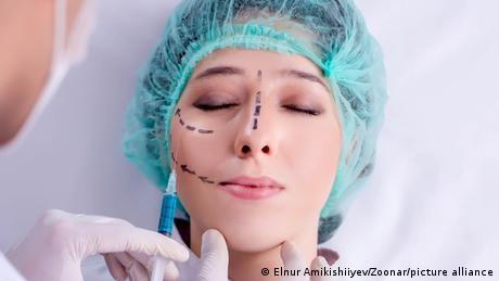 Ein plastischer Chirurg bereitet das Gesicht einer Patientin für eine Schönheits-OP vor