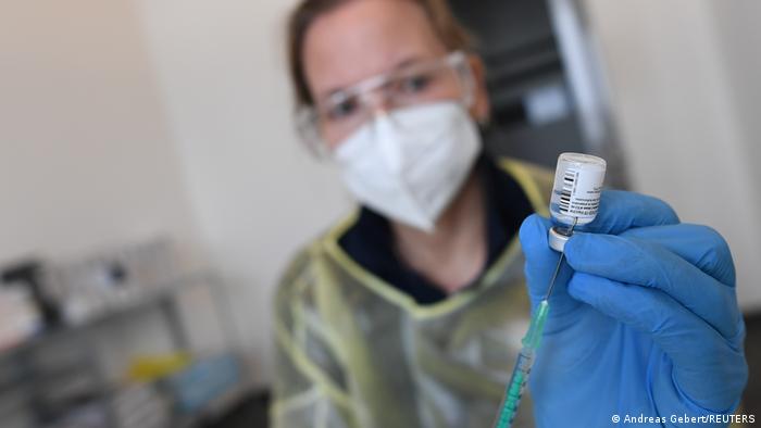 A health care provider prepares a syringe with a coronavirus vaccine