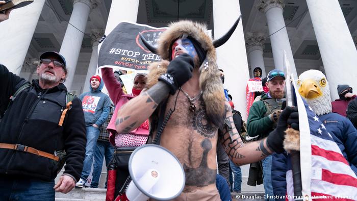 Jake Angeli, a QAnon supporter, seen with horns and megaphone in front of the Capitol