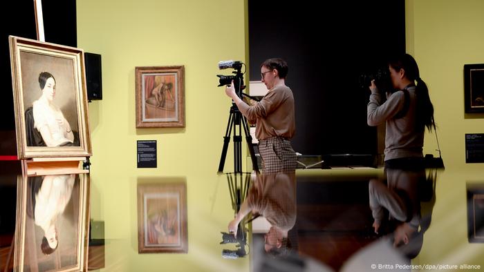 Photographers taking pictures of Portrait of a Seated Young Woman by Thomas Couture, which was also identified as Nazi-looted art.