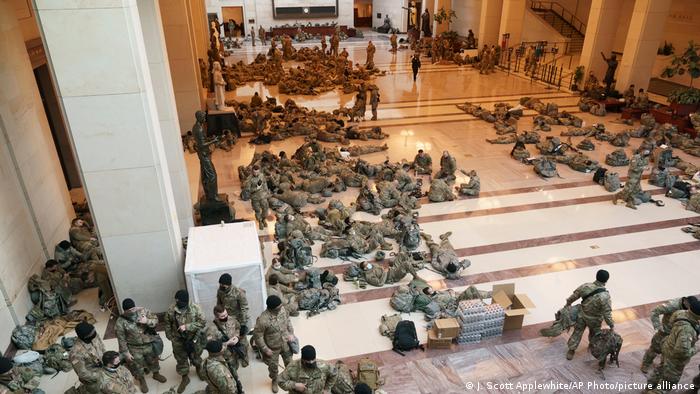 National Guard members standing, sitting, and laying down inside the US Capitol