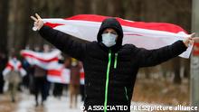 A demonstrator wearing a face mask to help curb the spread of the coronavirus waves an old Belarusian national flag during an opposition rally to protest the official presidential election results in Minsk, Belarus, Sunday, Dec. 13, 2020. Protests in Belarus have continued for almost four months after President Alexander Lukashenko won his sixth term in office in an election the opposition says was rigged. (AP Photo)