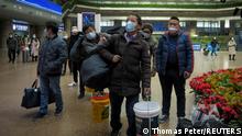 Travellers wearing face masks, following the coronavirus disease (COVID-19) outbreak, walk with their belongings at a railway station in Beijing, China January 13, 2021. Picture taken January 13, 2021. REUTERS/Thomas Peter