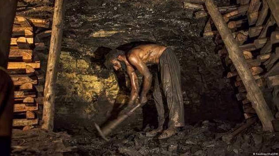 A man digs coal with a pick axe
