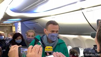 Навальный пытается пройти к своему месту в самолете