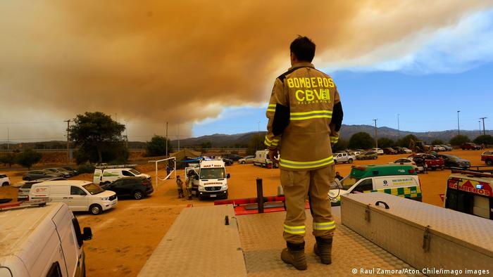 Foto de un bombero frente a un cielo lleno de humo por incendios en Chile