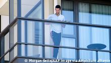 Serbia's Novak Djokovic stands on the balcony at his accommodation in Adelaide, Australia, Tuesday, Jan. 19, 2021. Australian Open tournament director Craig Tiley defended Djokovic for appealing to Australian Open organizers to ease restrictions so players could move to private residences with tennis courts. (Morgan Sette/AAP Image via AP)