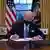 Джозеф Байден подписывает указы на фоне флага США в Овальном кабинете Белого дома