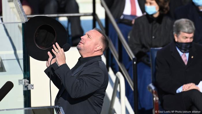 Garth Brooks, hat in hand, looks up at the sky