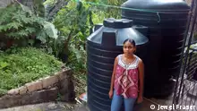 Credit:Jewel Fraser, taken November 2020.
ALT: Nickia DeMatas stands in front of her water tanks in Trinidad, Caribbean. Schlagwörter: Global Ideas, Caribbean, water shortages 