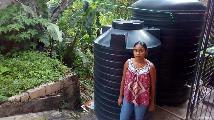 A neighbor of Noreen Nunez in the St. Augustine neighborhood of Trinidad stands next to her water tanks