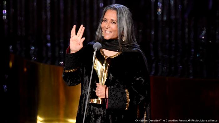 Deepa Mehta, a woman stands on stage at a microphone Deepa Mehta, a woman stands on stage at a microphone