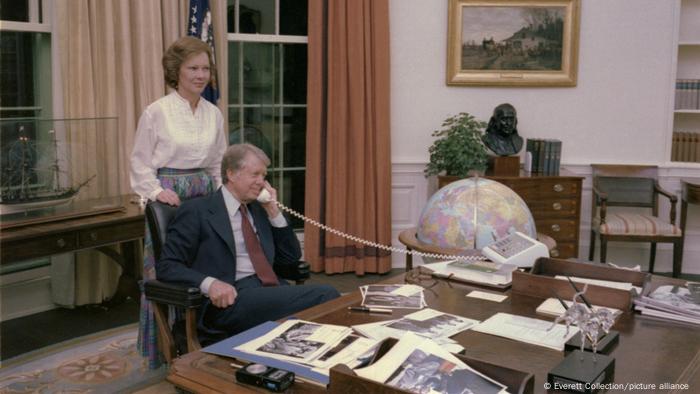 US-Präsident Carter sitzt 1978 telefonierend am Schreibtisch in seinem Büro im Weißen Haus, dahinter seine Frau Rosalynn