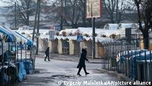 Two women walk past a closed street market in Ivano-Frankivsk, Western Ukraine, Friday, Jan. 8, 2021. Ukraine imposed a wide-ranging lockdown beginning Friday, closing schools and entertainment venues and restaurant table service through Jan. 25. (AP Photo/Evgeniy Maloletka)