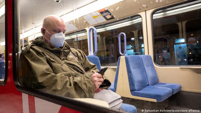 Muškarac sjedi u gradskoj željeznici s maskom na licu
