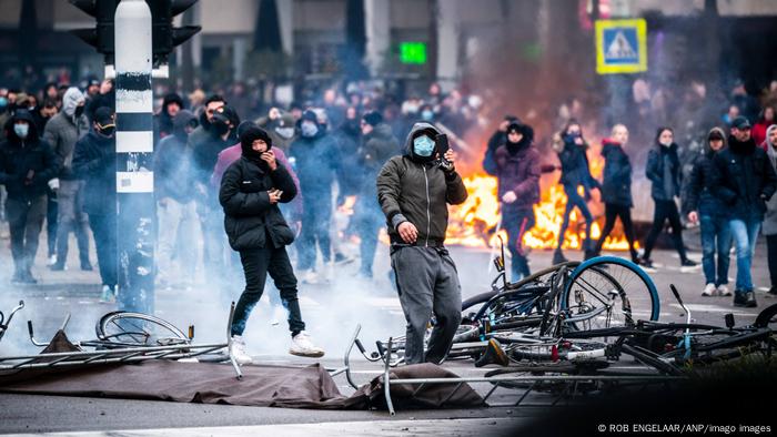 Manifestantes mascarados, fogo e fumaça em rua de Eindhoven, Holanda