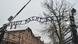 The entrance to the Auschwitz concentration camp. Above the gate are the words 'Arbeit macht frei' (work sets you free), in the background are brown-brick buildings with snow-covered roofs, Poland, January 26, 2019