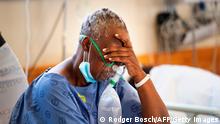 TOPSHOT - A patient with the COVID-19 breaths in oxygen in the COVID-19 ward at Khayelitsha Hospital, about 35km from the centre of Cape Town, on December 29, 2020. - The patents in this ward are not critically serious, but do require oxygen and to lie down. South Africa has become the first African nation to record one million coronavirus cases, according to new data published by the country's health ministry on December 27, 2020. Currently suffering a second wave of infections, of which the majority are a new variant of the coronavirus, South Africa is the hardest hit country on the African continent. (Photo by RODGER BOSCH / AFP) (Photo by RODGER BOSCH/AFP via Getty Images)