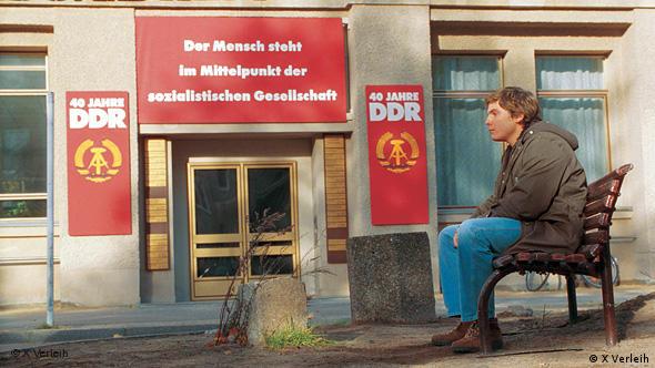 Daniel Brühl sitzt vor Eingang mit DDR-Parolen - Szene aus Good Bye, Lenin! (Foto: AP Photo/X-Filme, HO)