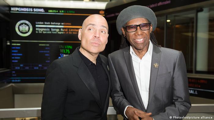 Merck Mercuriadis (left) and Nile Rodgers smile, Rodgers, on the right wearing glasses and a hat.