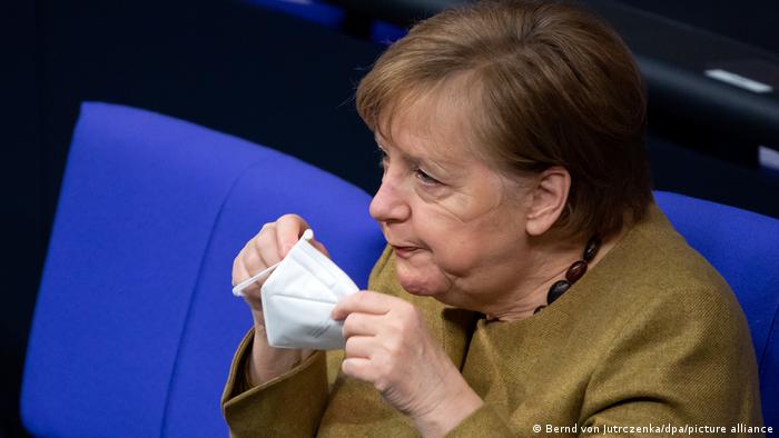 Angela Merkel puts on a face mask