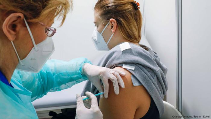 Profissional aplica injeção no braço de uma mulher